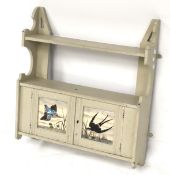 A wall mounted shelf and cupboard with painted bird decoration.