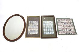 A bevelled edge oval wall mirror and three cricket related pictures.