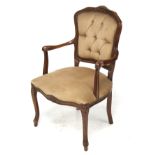 A wooden framed open armchair with brown button back upholstery.