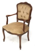 A wooden framed open armchair with brown button back upholstery.
