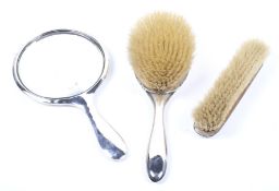 A silver backed mirror and two brushes.