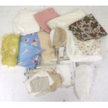 An assortment of textiles. Including embroidered tablecloths, crochet doilies, a quilt, etc.