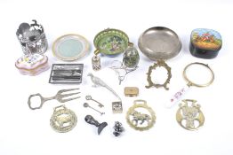 An assortment of collectables. Including a French ceramic floral box, horse brasses, a shaker, etc.