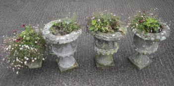 A set of three composite stone garden urns and one other.