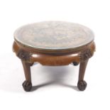 A 20th century oriental circular coffee table with carved polychrome figures to centre.