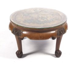 A 20th century oriental circular coffee table with carved polychrome figures to centre.