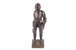 A Victorian metal model of a suit of armour. With articulated arm and legs, fixed to a wooden base.
