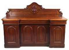 A Victorian mahogany inverted breakfront sideboard with carved crest.