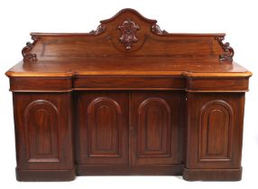 A Victorian mahogany inverted breakfront sideboard with carved crest.