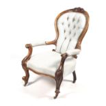 A Victorian walnut carved open armchair. With buttonback upholstery to the spoon back, H96.