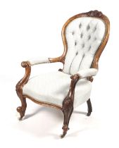 A Victorian walnut carved open armchair. With buttonback upholstery to the spoon back, H96.