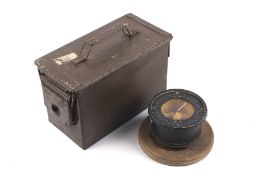 A military compass mounted on a wooden base and and an H83MK2 ammunitions box