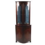 A Georgian mahogany bow front corner cabinet with an associated astragal glazed top section.