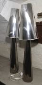 A pair of tall silvered conical shaped electric lamps,