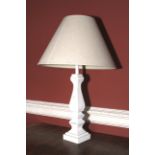 A white painted wooden vase shaped lamp and shade.