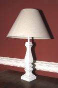 A white painted wooden vase shaped lamp and shade.