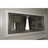 A contemporary bevelled glass mirror with silvered frame. 52cm H x 134cm W.