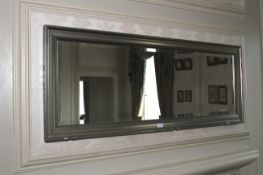 A contemporary bevelled glass mirror with silvered frame. 52cm H x 134cm W.
