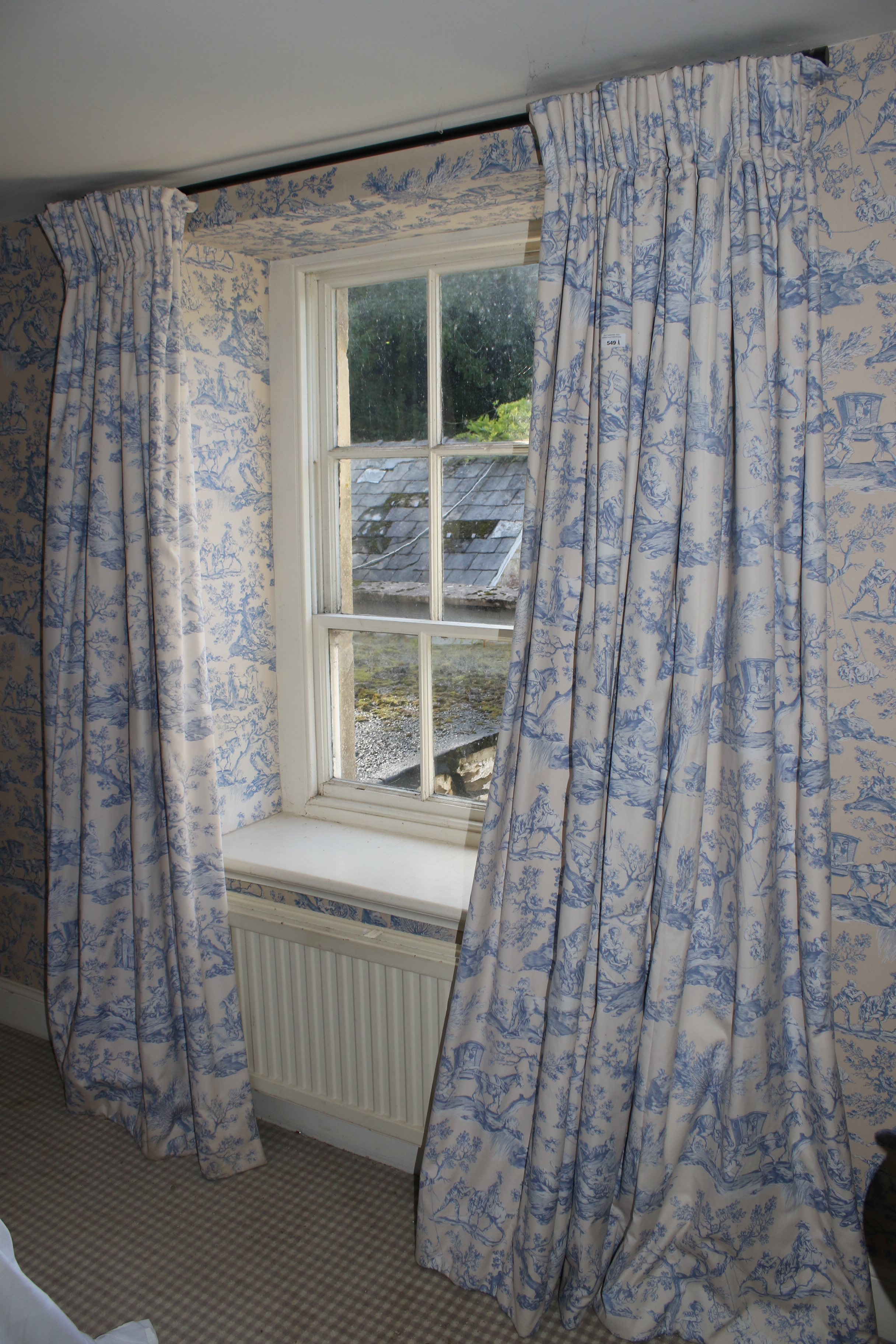 A pair of lined cotton curtains. Printed in blue and white with countryside scenes.