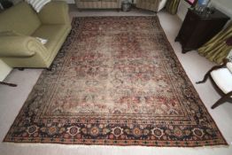 A large Persian woollen rug, 382cm x 272cm, with red ground with blues,