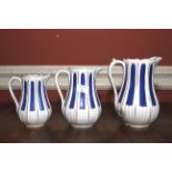 A set of three English white ceramic graduated jugs. White and blue decoration, tallest 22cm H.