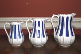 A set of three English white ceramic graduated jugs. White and blue decoration, tallest 22cm H.