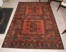 An early 20th century machine made woollen rug, 240cm x 170cm, with red ground having blue, black,