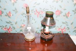 A contemporary crackle ice bottle shaped glass lamp together with a hand painted Toleware lamp,