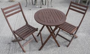 A three piece set of folding wooden garden furniture. Including two chairs and a table.