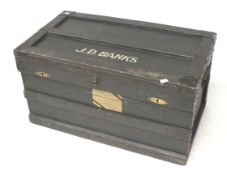A metal bound wooden travel trunk. 'J D Banks' painted on the lid.