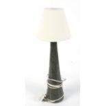 A contemporary conical-shaped polished serpentine lamp with cream lampshade.