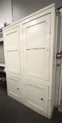 A vintage white painted pine 'Livery' cupboard. With four panelled doors.