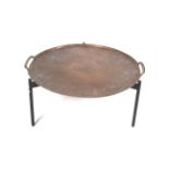 A large 'paella dish' style coffee table. On a tripod support.
