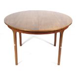 A mid-century Mcintosh extending circular teak dining table. On turned supports, label on the leaf.