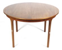 A mid-century Mcintosh extending circular teak dining table. On turned supports, label on the leaf.
