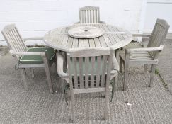 A teak extending garden table and four arm chairs. Comes with four seat cushions and a lazy suzanne.