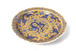 A 20th century Chinese dish. Printed with blue dragons on a yellow ground, Diameter 31.
