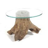A natural tree trunk and glass top oval coffee table.