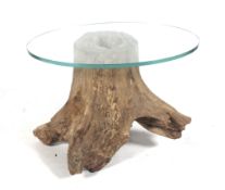 A natural tree trunk and glass top oval coffee table.