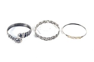 Three silver bangles. Including a snake example and another with a Celtic weave, 42.