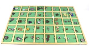 A large collection of enamel badges, medals and brooches pinned to a display board.