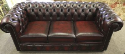 A contemporary burgundy red leather Chesterfield three seater sofa.