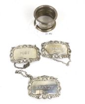 A silver napkin ring and three silver decanter labels.