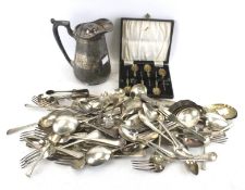 A plated and engraved straight tapering jug and collection of silver-plated flatware.