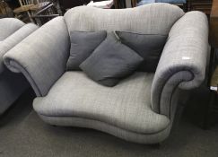 A contemporary grey upholstered two seater sofa with scroll arms. On turned tapering supports.