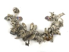 A silver 'charm' bracelet, hung with a large quantity of charms.