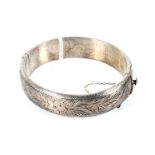 A vintage silver foliate engraved hollow hinged bangle. Hallmarks for Birmingham 1965, approx. 18.