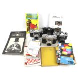 An assortment of cameras, lenses, photography books and camera manuals.