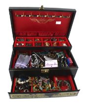 A black leather bound jewellery box containing a quantity of costume jewellery.