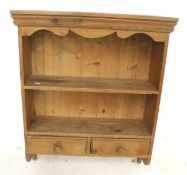 A pine wall shelf unit. With a single shelf positioned over two drawers.